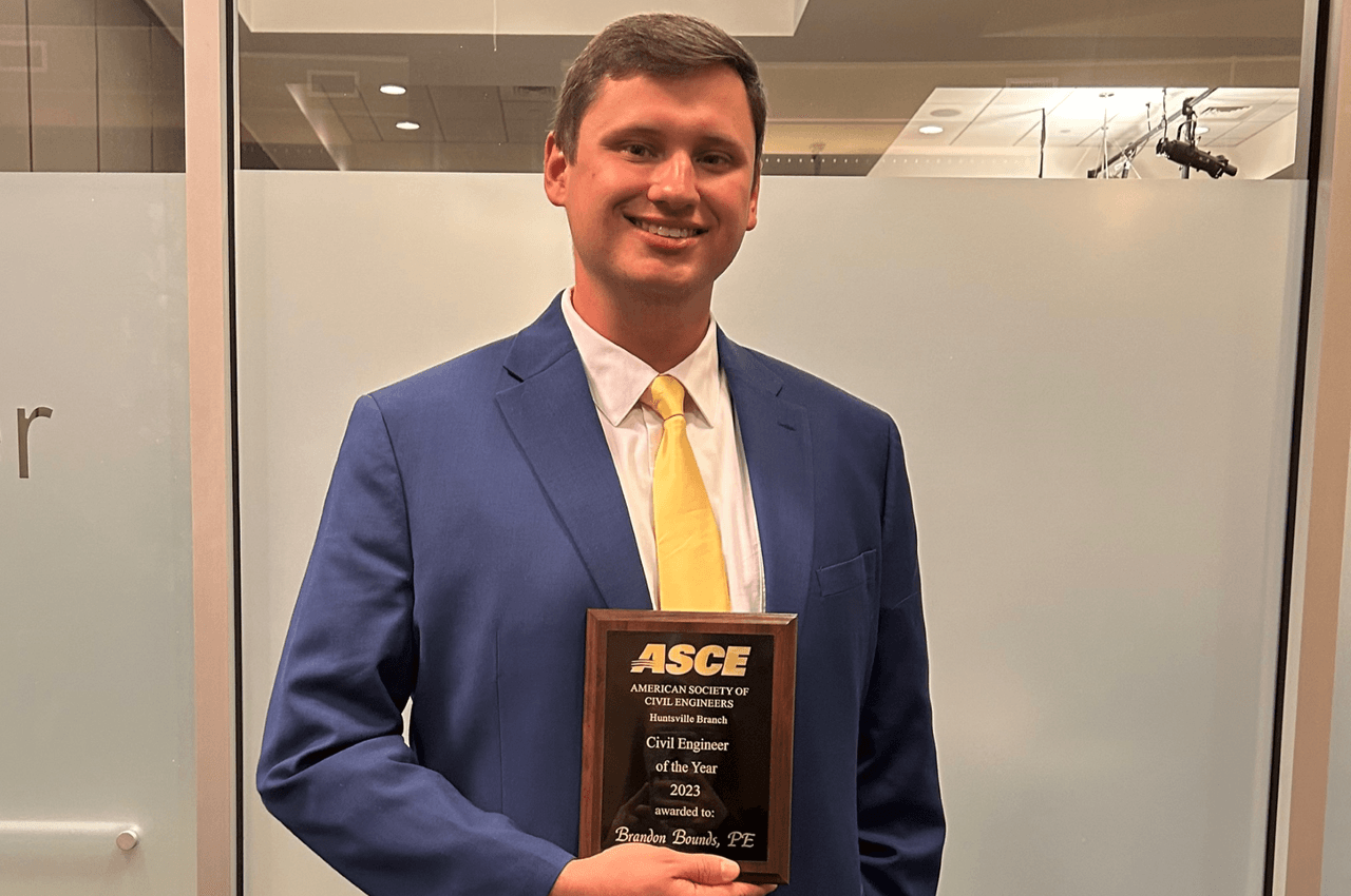 Man in suit holding Civil Engineer of the Year award.