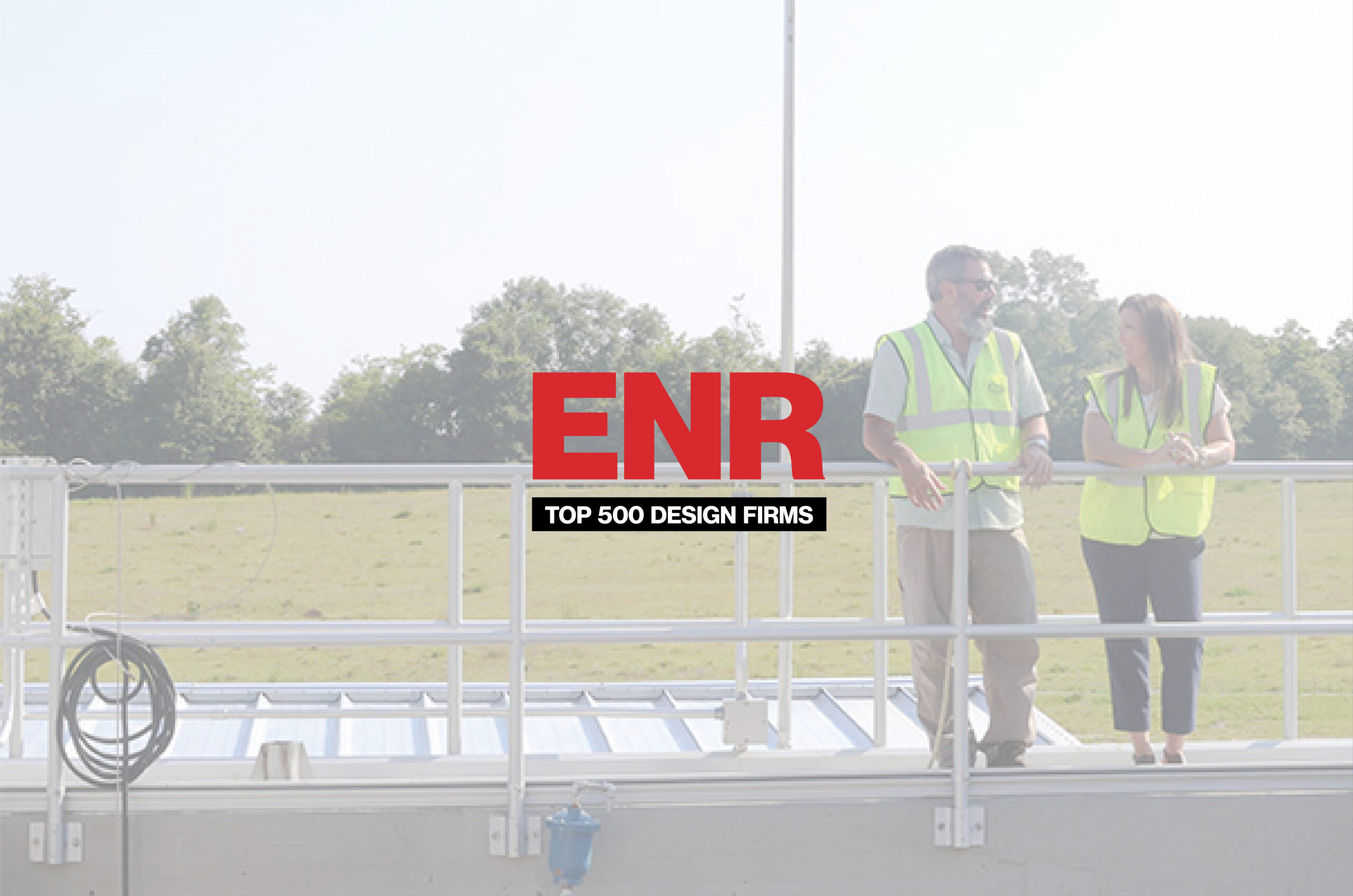 Two engineers wearing safety vests stand on a platform with the ENR Top 500 Design Firms logo.